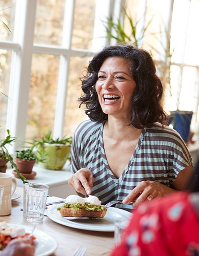 Woman smiling while eating at restaurant with friends