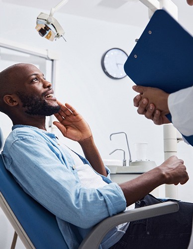 Man smiling at dentist holding clipboard