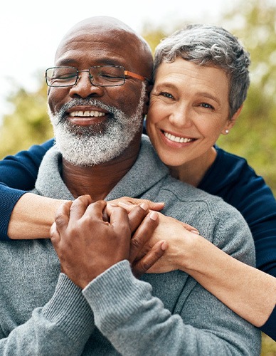 Senior couple smiling while hugging on beach