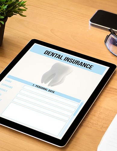 Dental insurance form on tablet next to notepad