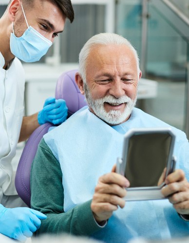 Man smiling at reflection next to dentist