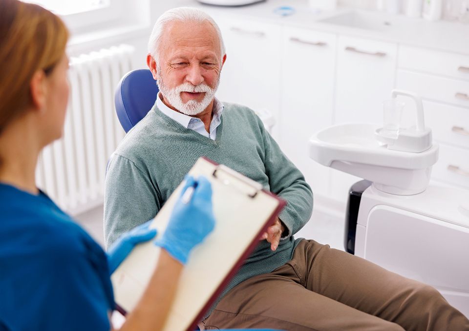 Dental assistant taking notes on clipboard while talking to patient