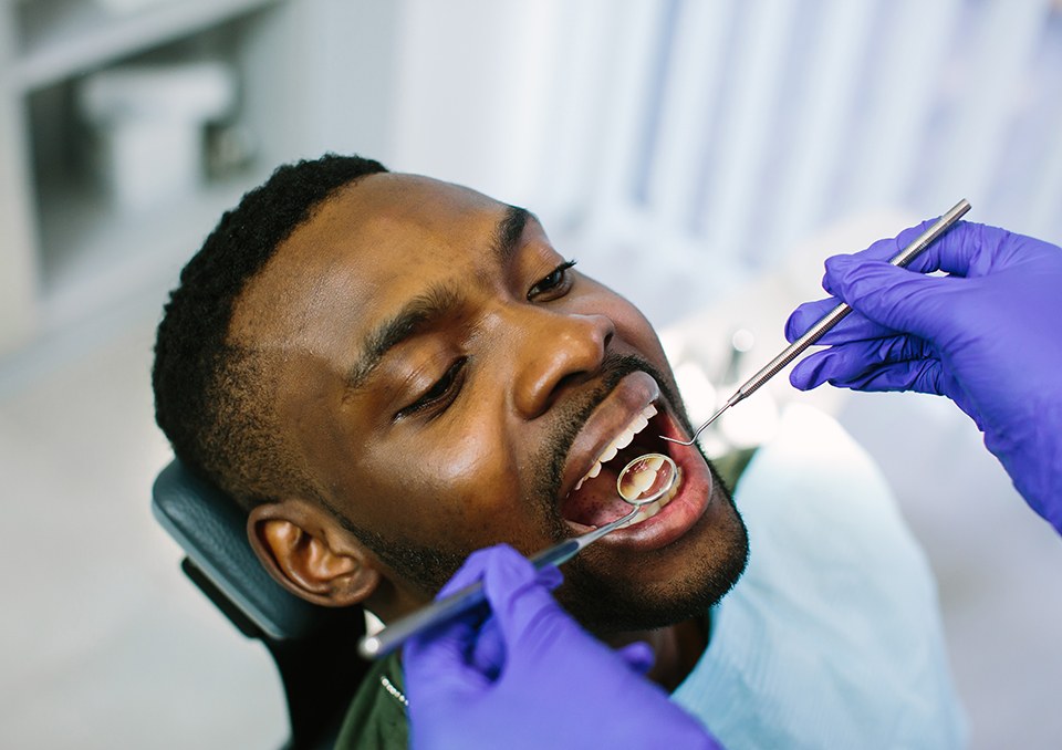 Dentist examining patient's teeth with dental mirror