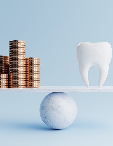 Large model tooth and pile of coins balanced on a ball and plank scale