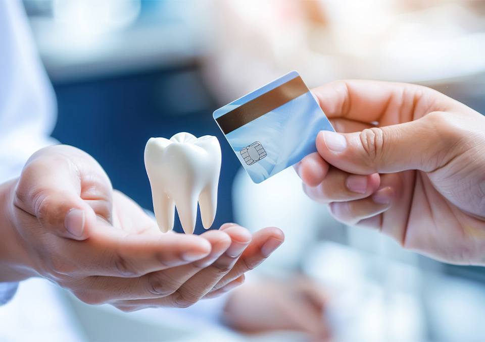 Dentist handing over large tooth and receiving a sky blue credit card