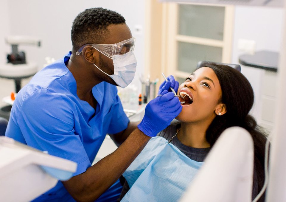 Dental assistant examining patient's teeth with dental tools 