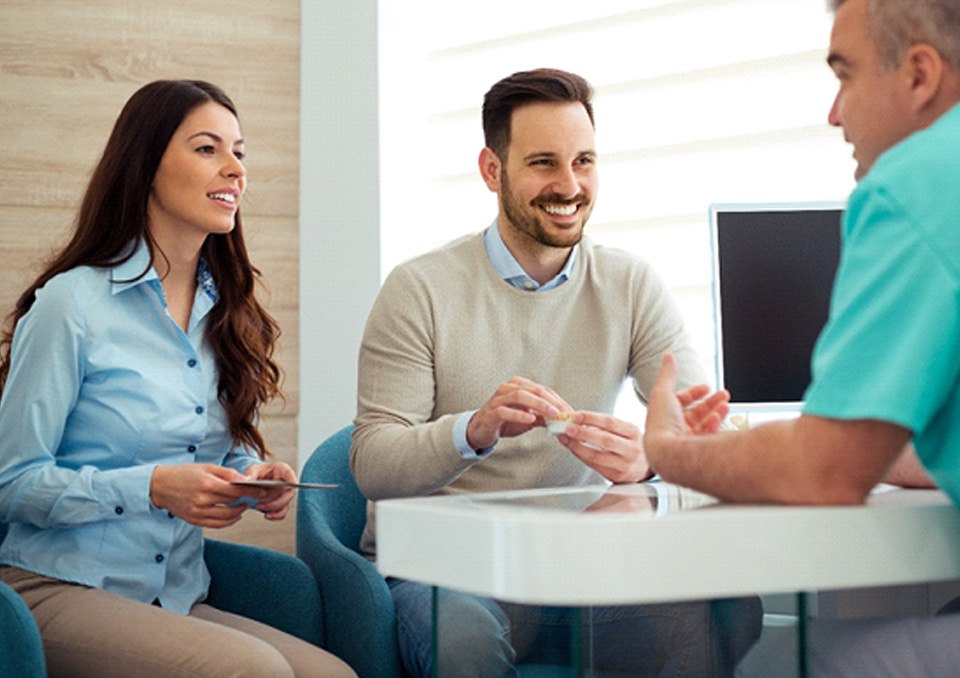 Dentist and couple talking in dental office