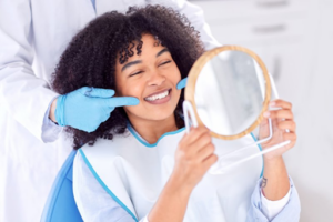 Woman smiling as dentist shows her her newly cleaned teeth in mirror